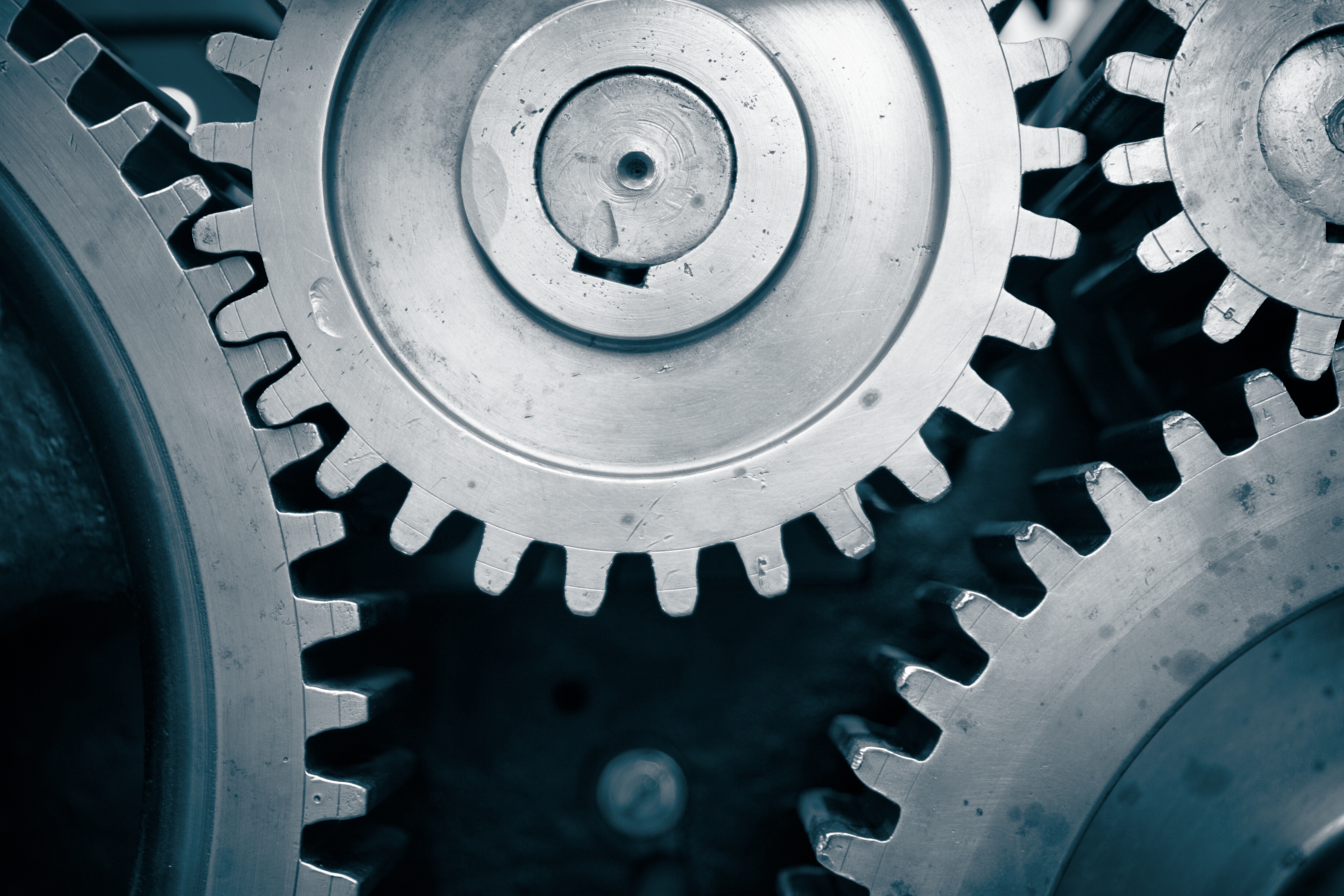 Close up of interlocking metal gears with visible wear and scratches on their surfaces.