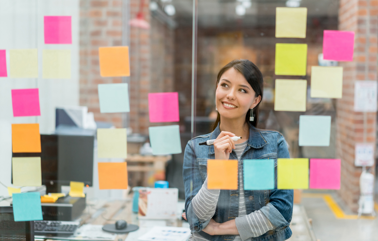 Latin American woman thinking of creative sales ideas at the office to put in a wall chart