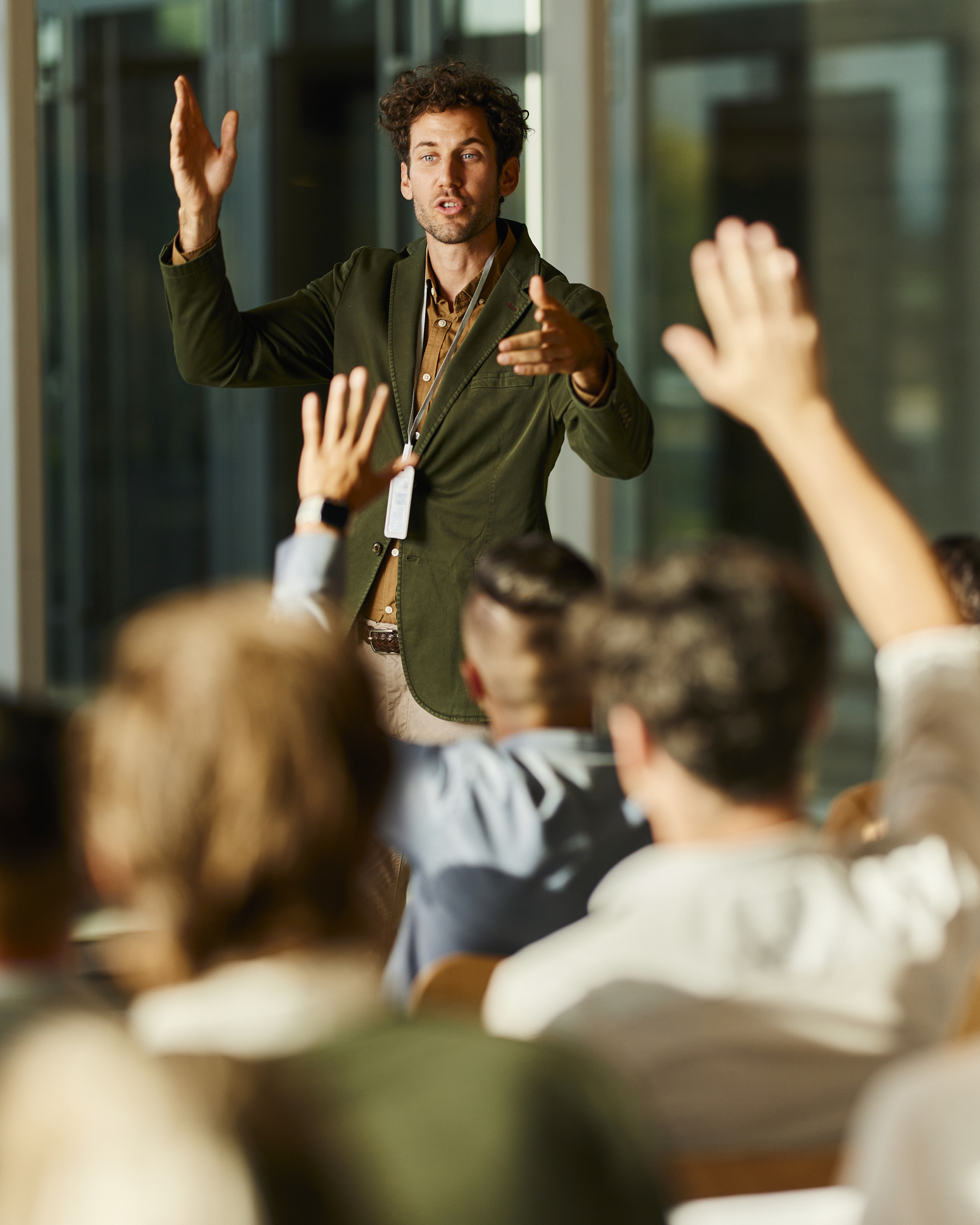 Man presenting to group with raised hands