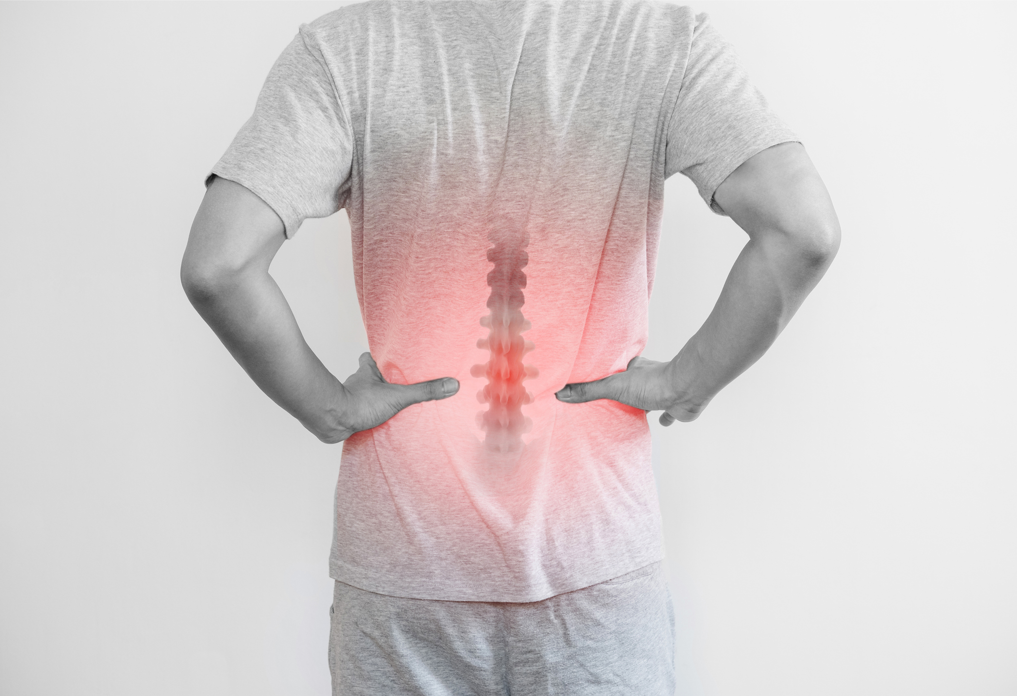 A person points to their lower back with a red overlay and spine graphic highlighting the area of pain.